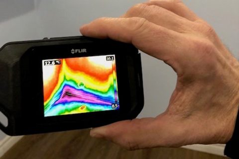 Hand holding a thermal camera searching for hidden mold